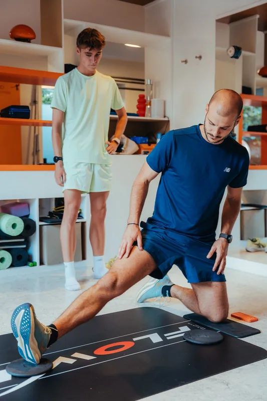 Kinésithérapeute qui montre une fente à un jeune sportif, dans la salle du centre