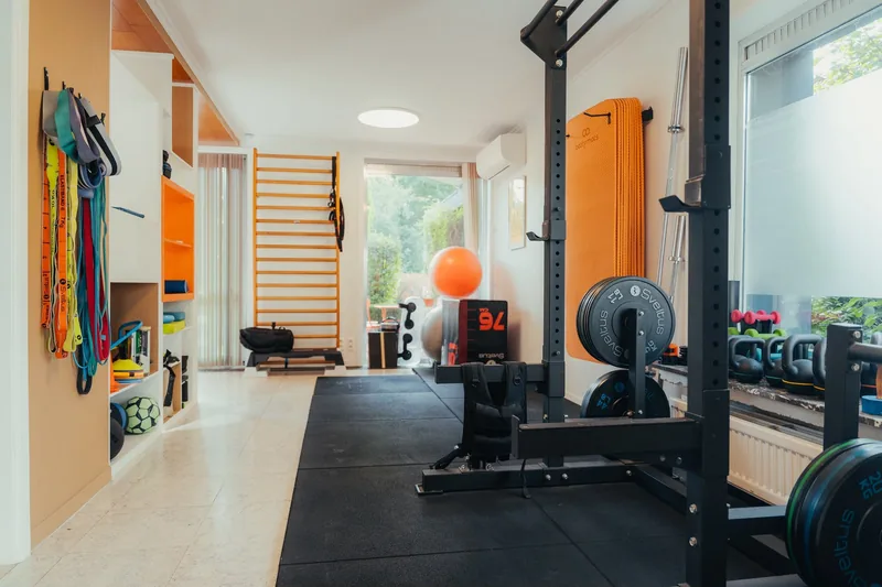 Salle d'entraînement du centre avec rack à poids, kettlebells, élastiques et espalier