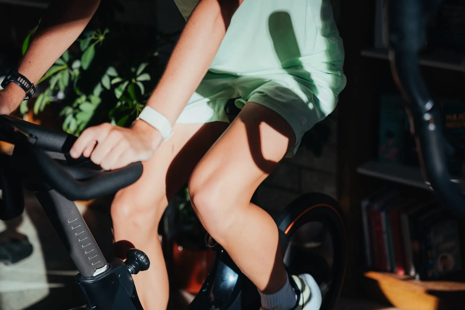 Gros plan des jambes d'une personne pédalant sur un home-trainer en intérieur
